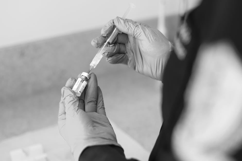 A healthcare worker prepares a syringe with medication in a clinical setting.